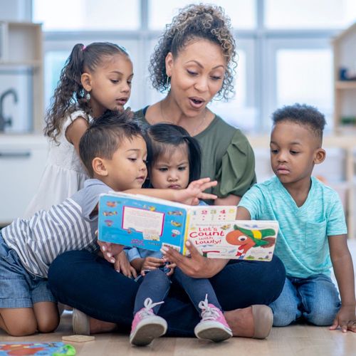 a daycare worker reading a book with young children
