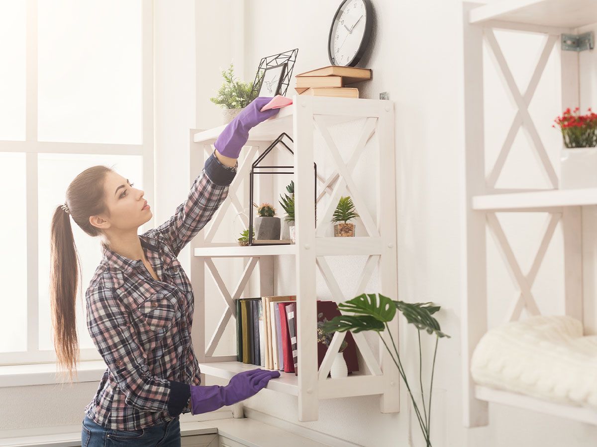 woman cleaning top shelf