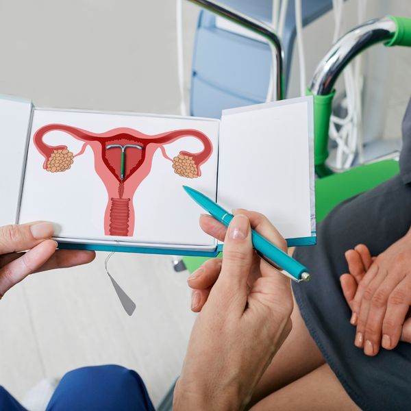 A minimalist medical illustration of a T-shaped IUD device on a light blue background. A minimalist medical illustration of a T-shaped IUD device on a light blue background.