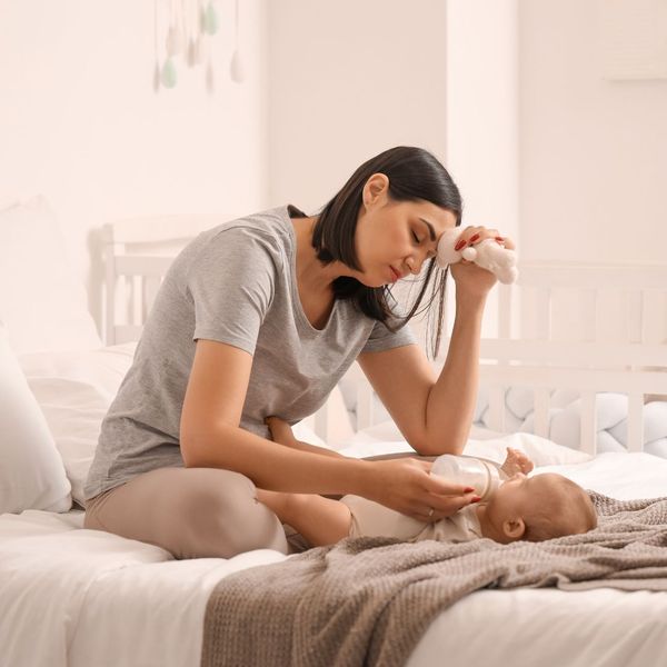 a tired woman feeding her baby on the bed