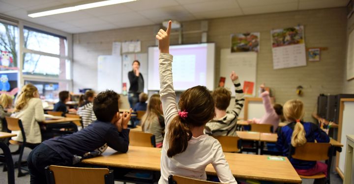girl in classroom raising hand
