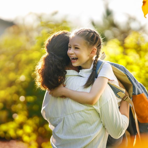 mom holding young daughter with backpack on