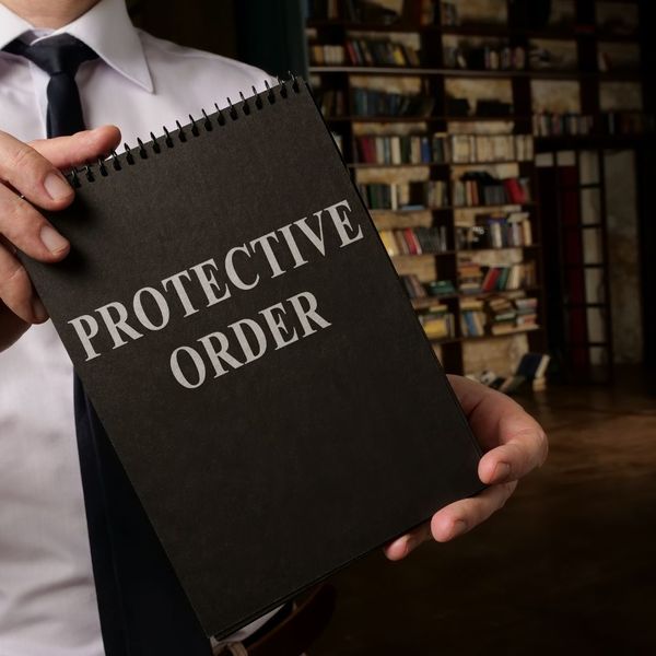 A man holding a notepad that says protective order.