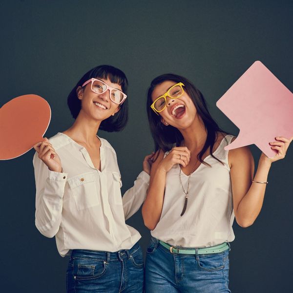 two women holding speech board