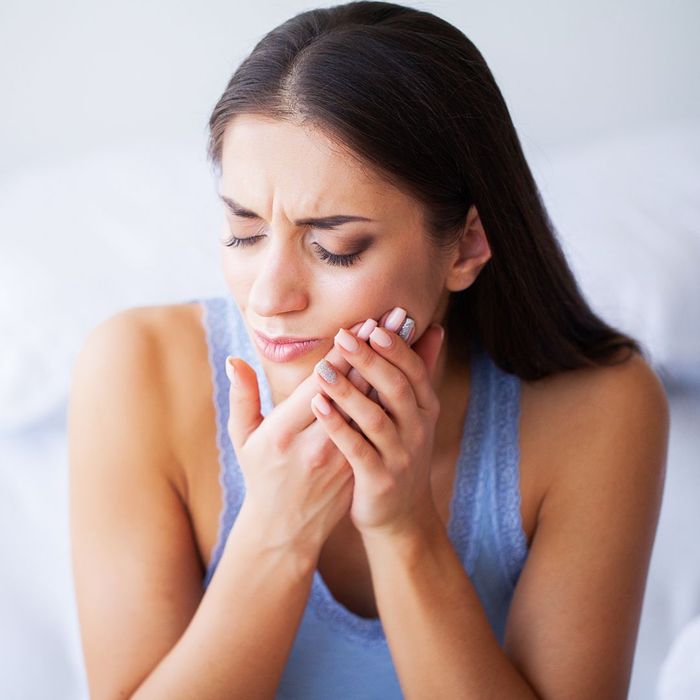 woman with tooth pain, hands against cheek