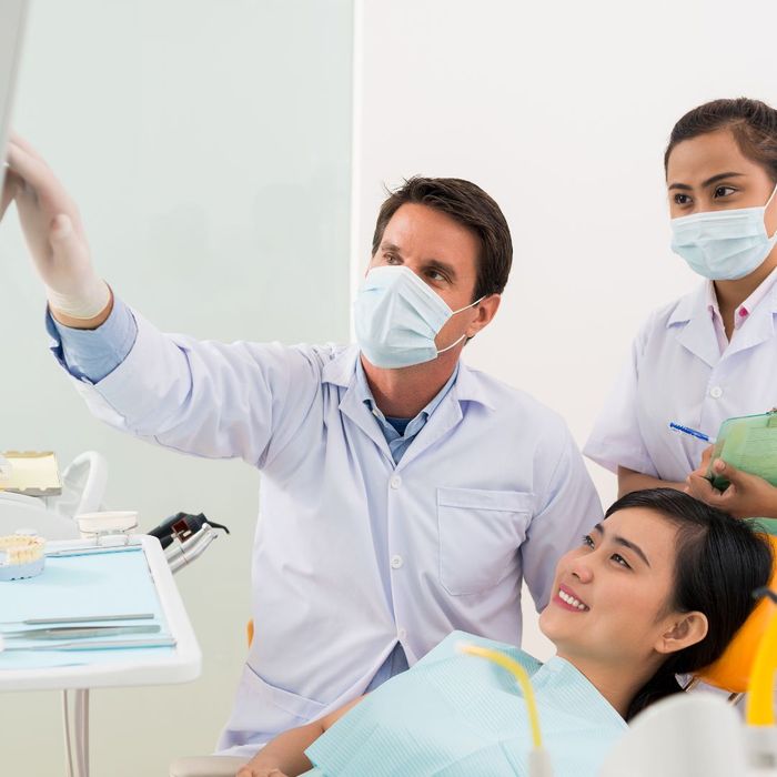 Dentist, assistant, and patient looking at screen