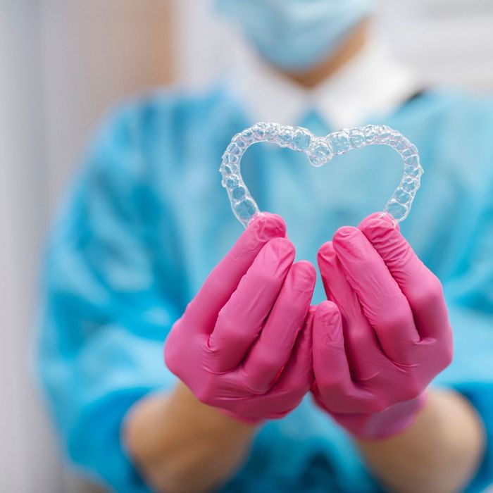 Orthodontist holding dental aligners in a shape of a heart