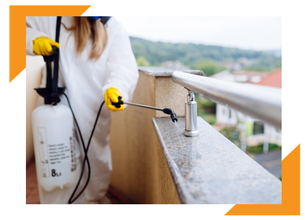 Exterminator spraying a balcony ledge for pests. Exterminator spraying for pests