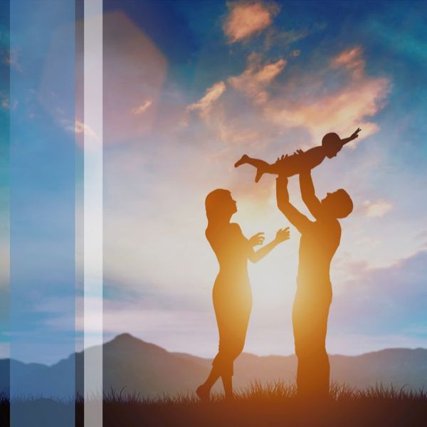 Parents holding a child above their head with sunset in the background