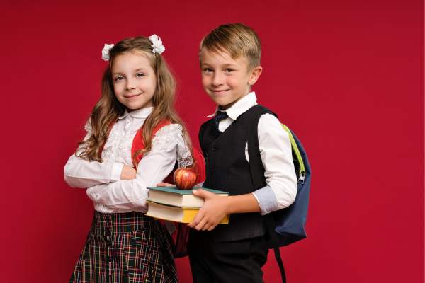 two kids wearing backpacks, holding books.