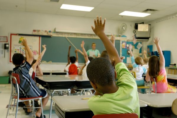 kids raising hands in classroom