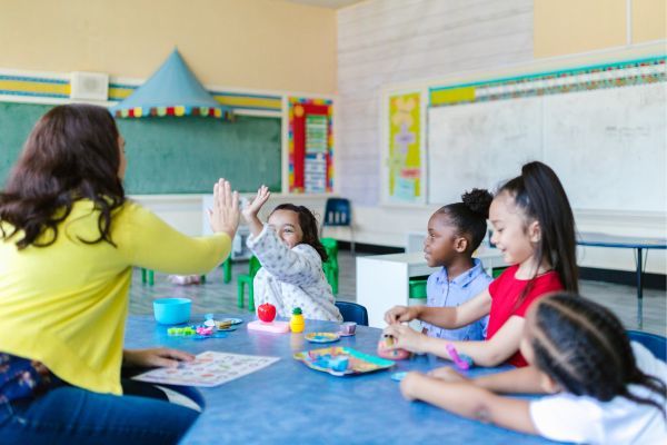 kid in classroom high fiving teacher