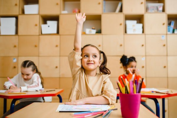 girl raising her hand in classroom