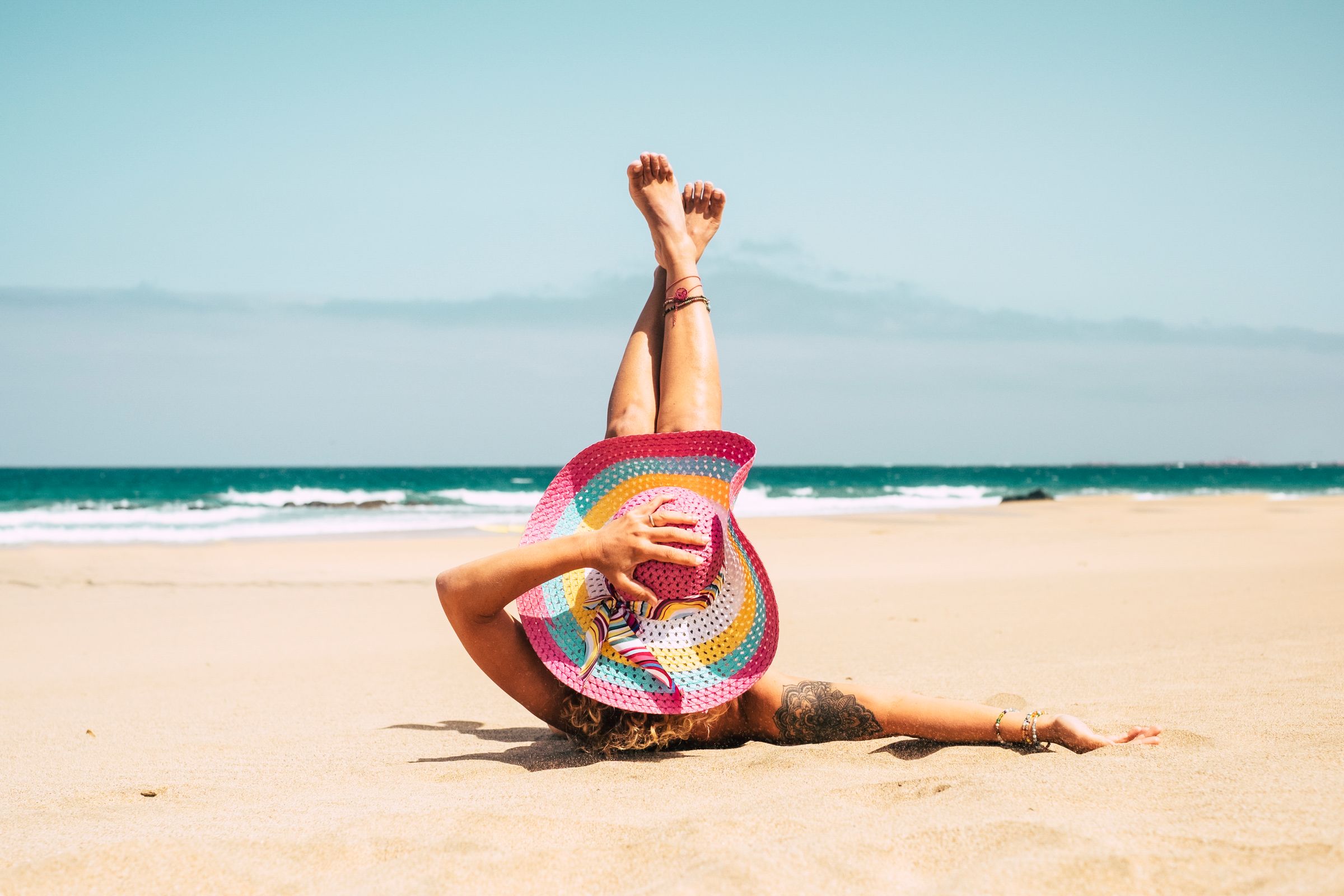 woman-with-colorful-hat-enjoy-the-beach-laying-on--CNK7TDX.jpg