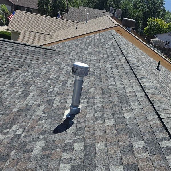 A newly installed architectural shingle roof with a modern color blend and a new silver vent pipe. A newly installed architectural shingle roof with a modern color blend and a new silver vent pipe.