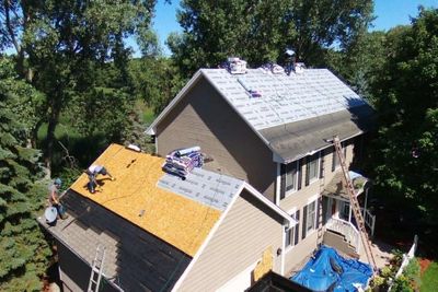 An aerial view of a large residential roof replacement in progress with new underlayment and shingles being installed. An aerial view of a large residential roof replacement in progress with new underlayment and shingles being installed.