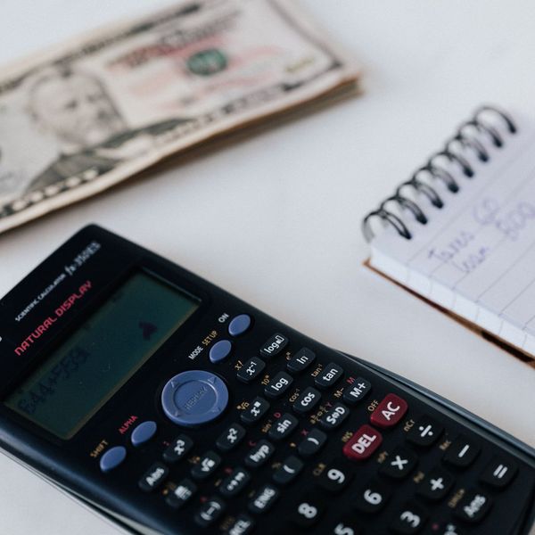 calculator and money on a desk next to a notepad