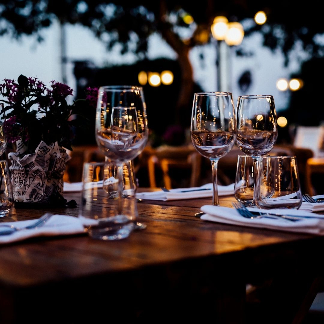 a wooden table set with fine dining utensils and glasses