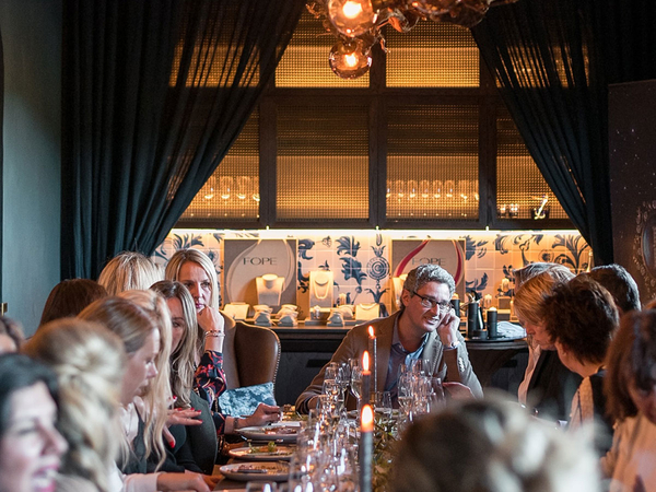 A large group of people sitting at a long, nicely set table.