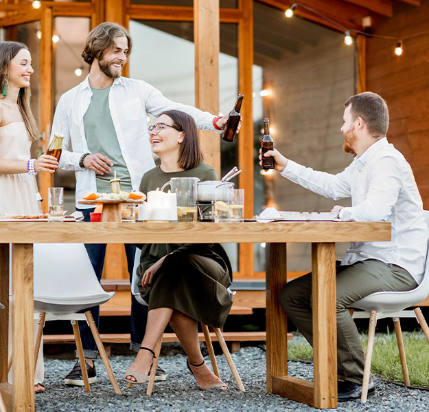 A group of friends saying, "Cheers" at an outdoor table.