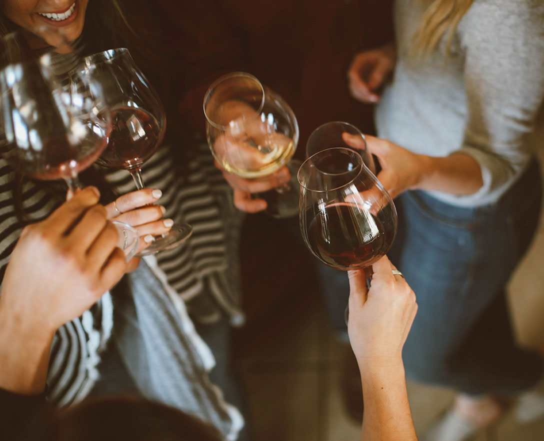 Women standing together in a circle clinking their wine glasses.