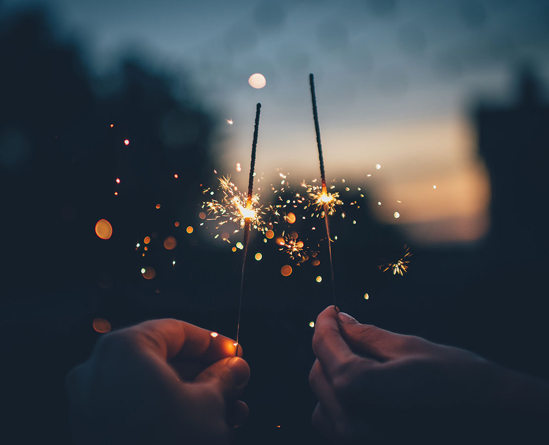 Two sparklers being held in the dark.