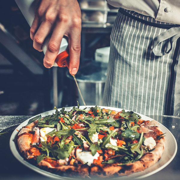 image of a chef drizzling oil over a gourmet pizza