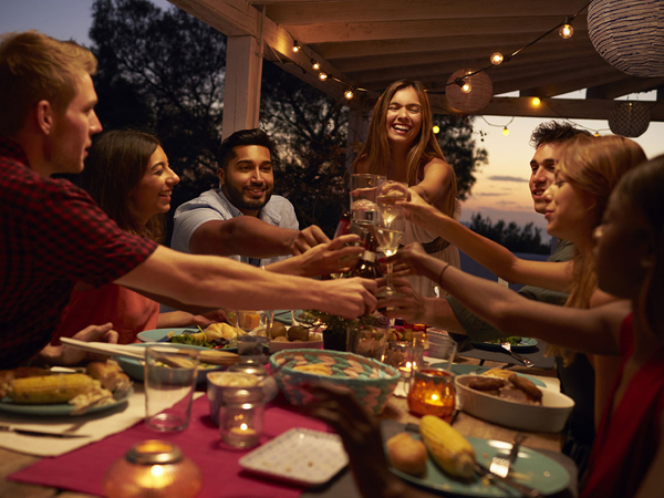 image of a group of people eating around a dinner table outdoors on a patio in the evening