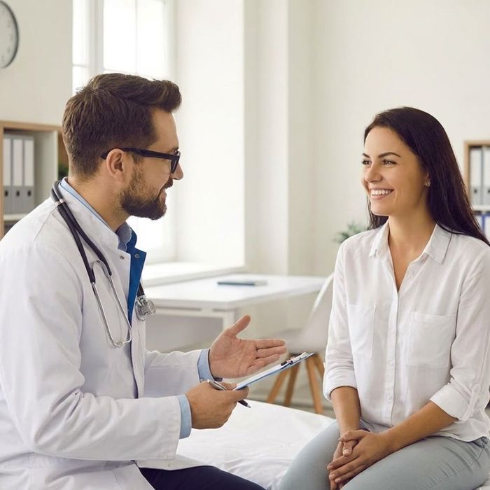 A doctor and a smiling patient together in a modern, naturally lit clinic consultation room.