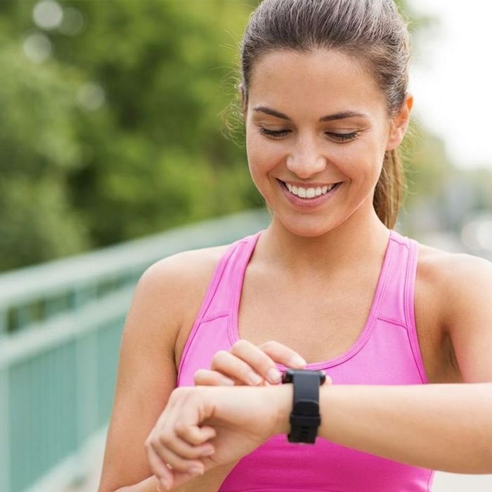 A smiling woman looks at her smartwatch.