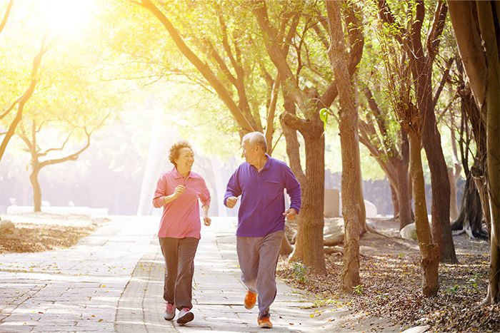 A mature couple running outdoors and happy