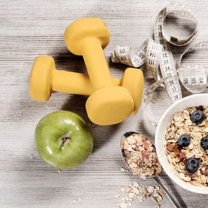 small dumbbells, an apple, granola and a tape measure on a table