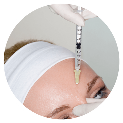 Close-up of syringe injecting into woman's forehead