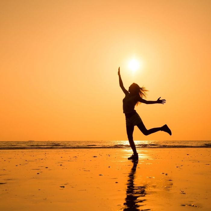 someone dancing on a beach during a sunset