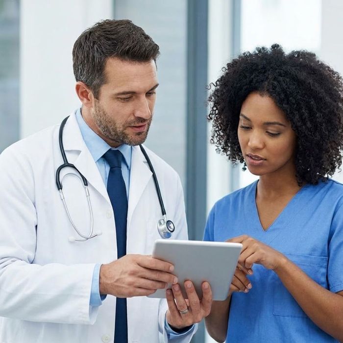 Two health professionals, reviewing data on a tablet.