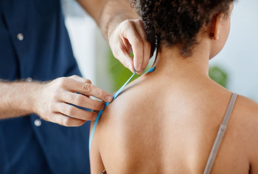 physical therapist taping womans shoulder