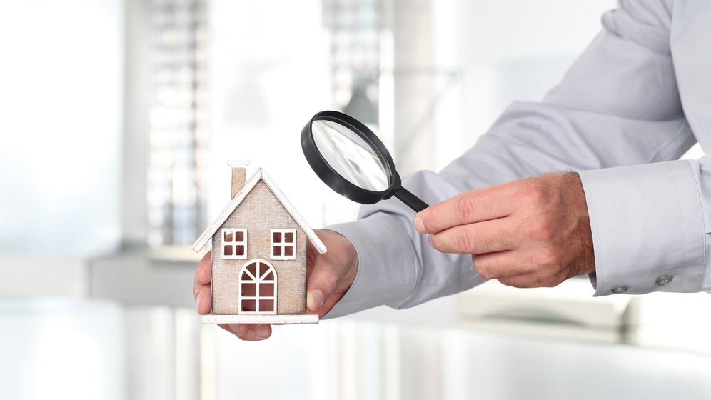 person holding a magnifying glass to a model home