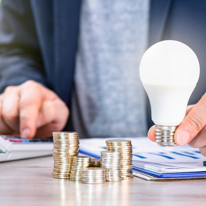 Man holding lightbulb with stack of coins