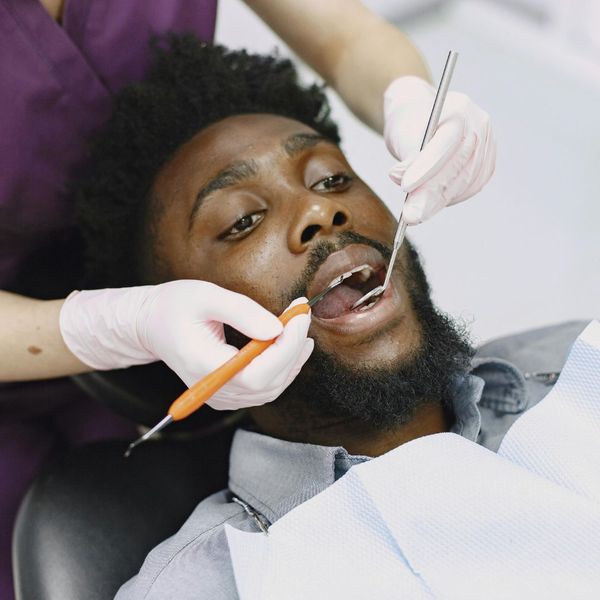 dental assistant cleaning man's teeth