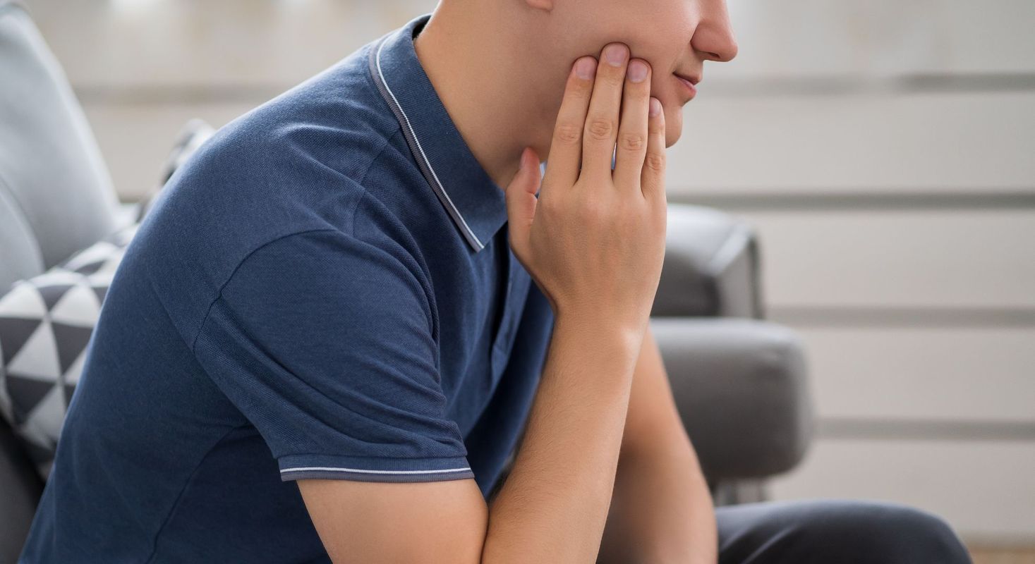 person touching face with tooth pain