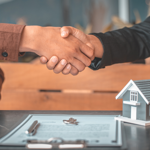 shaking hands over model home and contract