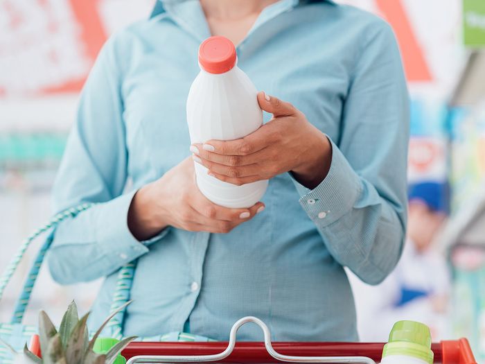 Woman reading nutrition label on container of milk