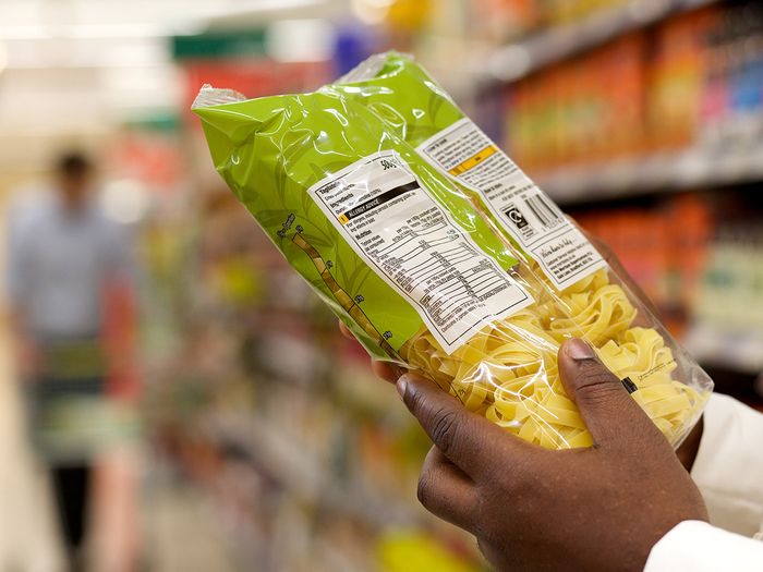 Person reading nutrition facts on bag of pasta