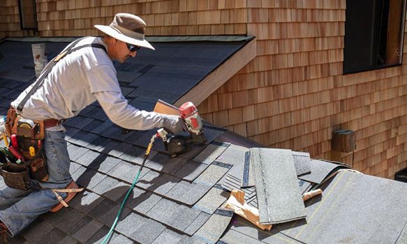 Roofer putting on new shingles on roof