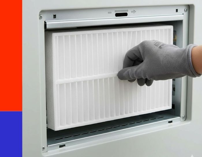 A close-up view of a technician’s hand in a protective gray work glove installing a clean, new white pleated air filter into a residential HVAC system.