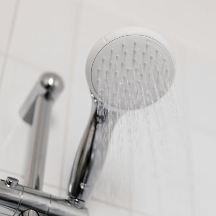 A shower head running hot water.