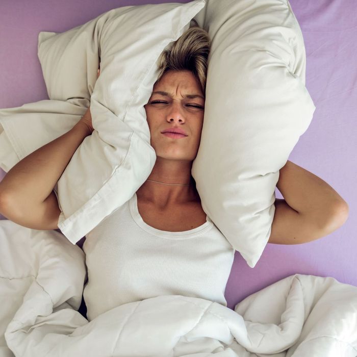 Women covering her ears with a pillow