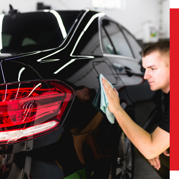 technician wiping exterior of black car
