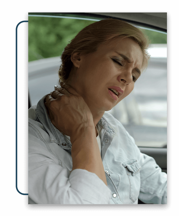 Woman sitting in her car, holding her neck in pain.