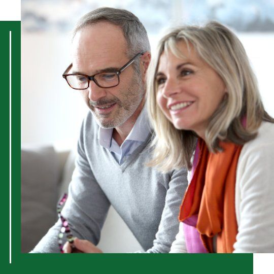 middle-aged couple talking to advisor, smiling
